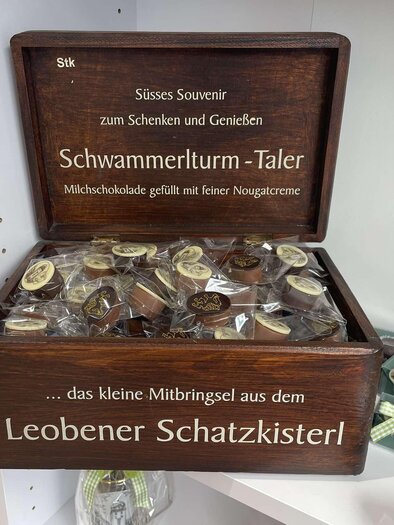 A wooden box labeled "Schwammerlturm-Taler" filled with round candies made of milk chocolate. Ideal as a souvenir for gifting and enjoying. | © Erzberg Leoben