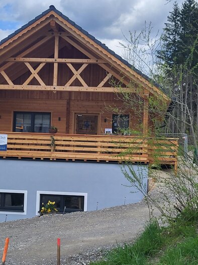 Ein traditionelles Holzhaus mit einem großen Balkon. Es liegt in einer ruhigen, natürlichen Umgebung mit grünen Bäumen im Hintergrund. | © TV Hochsteiermark |  Andrea Stelzer