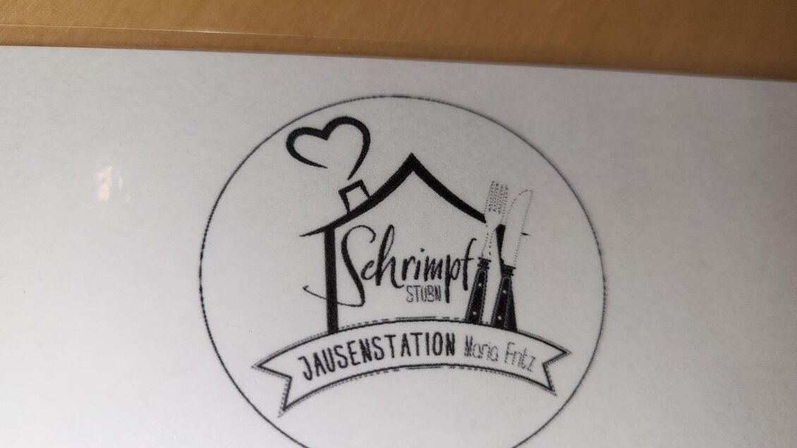 Ein Logo für die Jausenstation "Schmimpft". Es zeigt ein Haus mit Besteck und einem Herzsymbol. | © TV Hochsteiermark