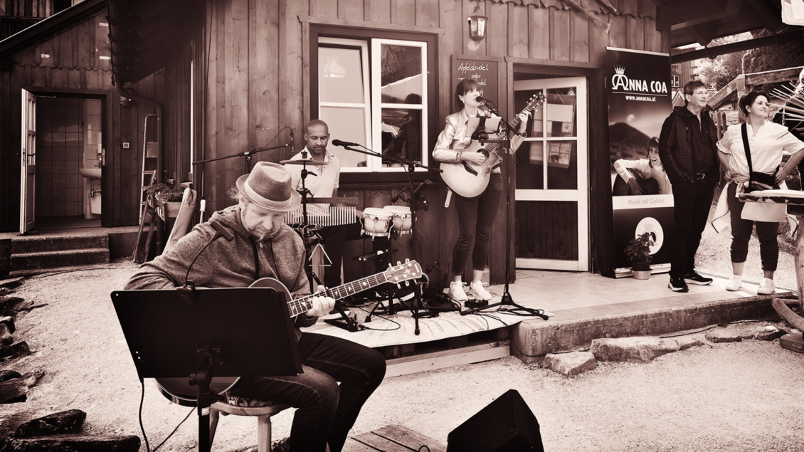 Eine kleine Live-Musikaufführung im Freien. Musiker spielen instrumentale Musik, während einige Zuschauer zuschauen. | © Christoph Knappe l