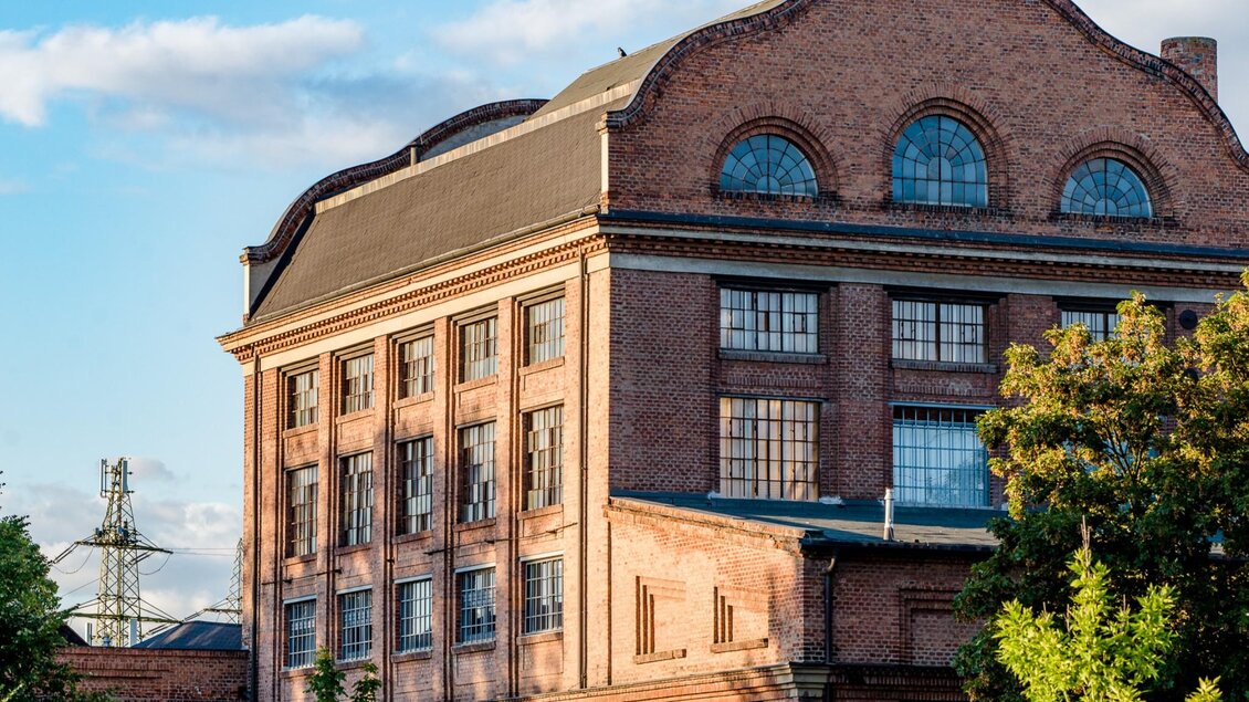 Rotes Ziegelgebäude der Seifenfabrik Graz mit markanter Dachform bei Sonnenuntergang. | © Graz Tourismus-Mias Photoart