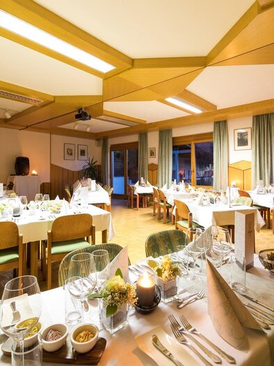 Ein elegantes Restaurant mit gedeckten Tischen und einer gemütlichen Atmosphäre. Große Fenster lassen warmes Licht herein und bieten einen Blick nach draußen. | © TV Region Graz - Harry Schiffer
