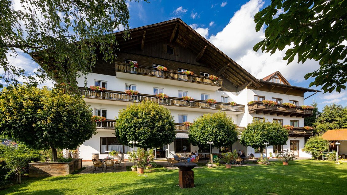 Ein ruhiges Hotelgebäude mit mehreren Balkonen und bunten Blumen. Der gepflegte Garten mit Bäumen lädt zum Entspannen ein. | © TV Region Graz - Harry Schiffer