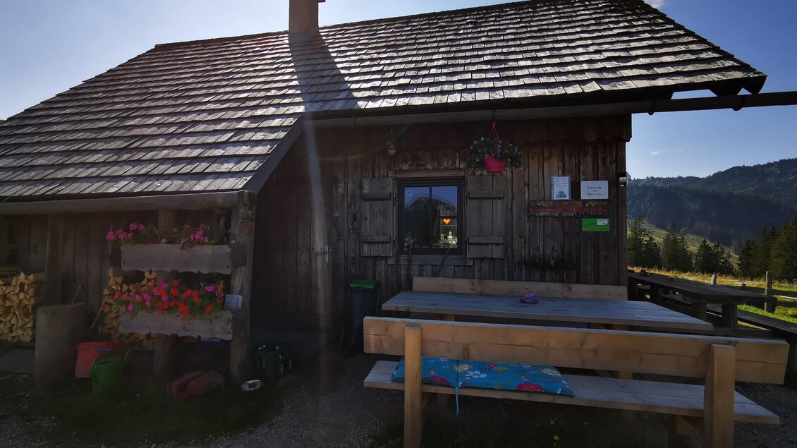 Eine gemütliche Hütte aus Holz mit einem schrägen Dach und blühenden Blumen. Draußen steht ein Tisch aus Holz im Freien. | © TV Hochsteiermark / Brigitte Digruber