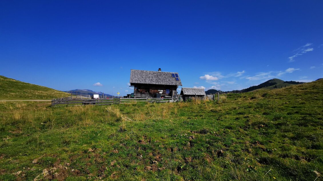 Eine idyllische Berghütte umgeben von grünen Wiesen und sanften Hügeln. Der Himmel ist klar und blau, was die ruhige Atmosphäre unterstreicht. | © TV Hochsteiermark / Brigitte Digruber
