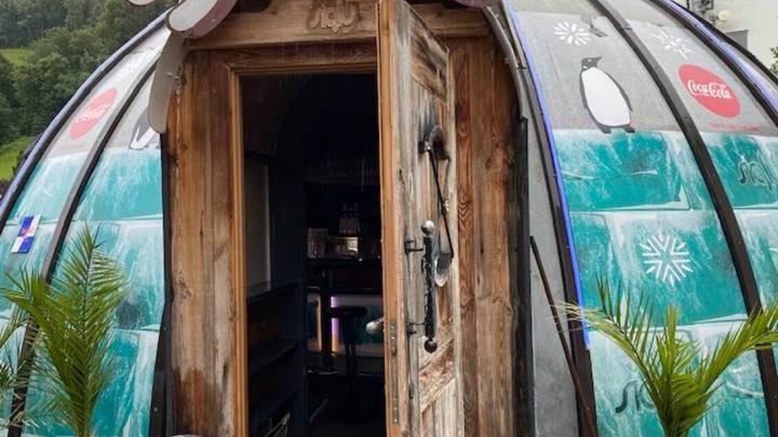 Ein einzigartiges, igluartiges Gebäude mit dem Namen "SIGLU". Es hat eine Holztür und steht vor einer bewaldeten Kulisse. | © Siglu-Bar Schladming