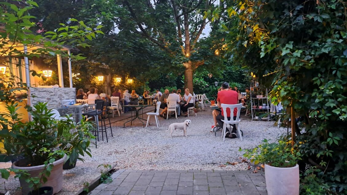 Gäste im abendlich beleuchteten Gastgarten des Restaurants Simply Greek Graz mit Bäumen und Lichtern. | © Galghoura