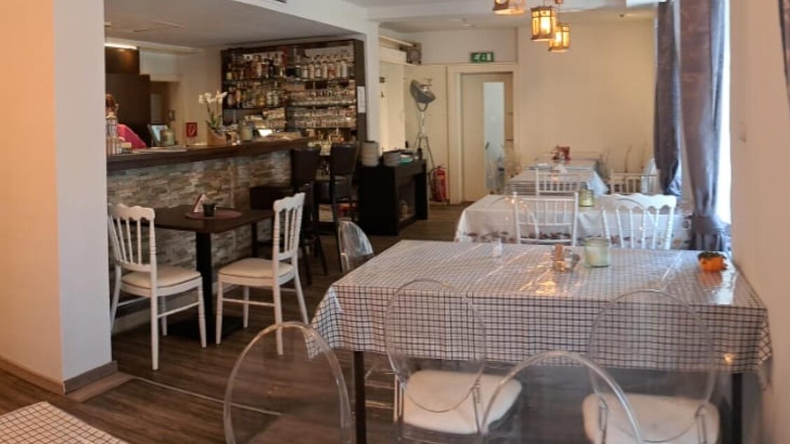 Tischreihe im Simply Greek Graz mit hellen Wänden, stilvollen Stühlen und warmem Licht. | © Galghoura