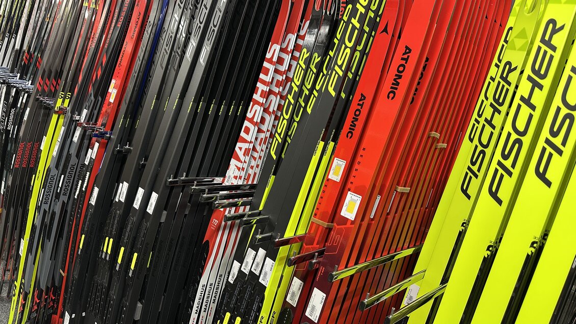 Eine große Auswahl an Skiern in verschiedenen Farben, darunter rot, schwarz und gelb. Die Skier sind ordentlich nebeneinander aufgereiht. | © SkiWilly