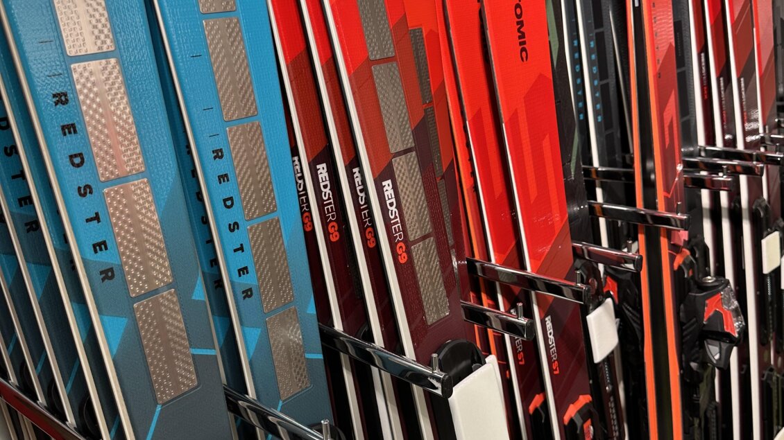 Eine Reihe von Skiern in verschiedenen Farben, hauptsächlich rot und blau. Sie sind kunstvoll nebeneinander aufgereiht. | © SkiWilly