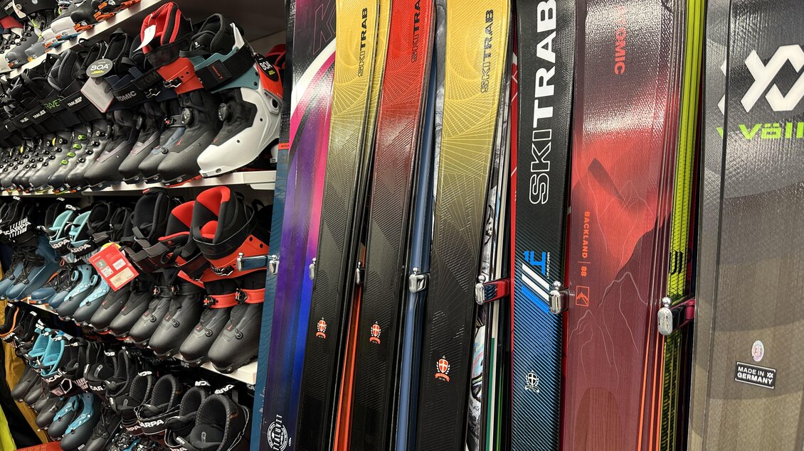 Eine Skiausrüstungs-Displays mit verschiedenen Skiern und Skischuhen. Die Skier sind bunt und modern, während die Skischuhe ordentlich angeordnet sind. | © SkiWilly