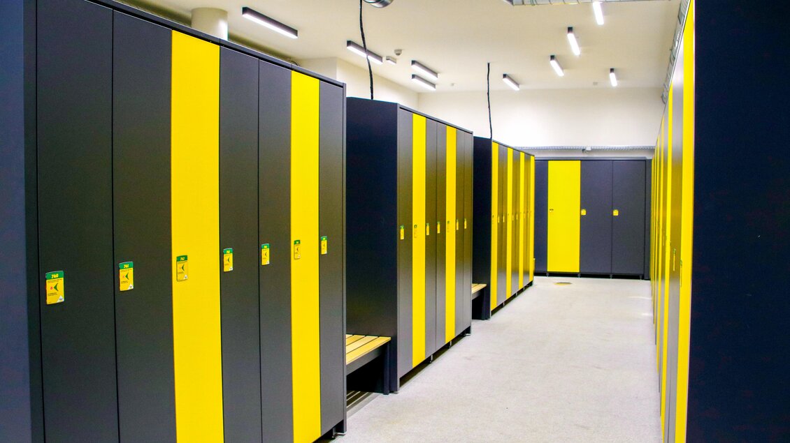 Ein moderner Umkleideraum mit schwarzen und gelben Schränken. Der Raum ist gut beleuchtet und aufgeräumt. | © Planai