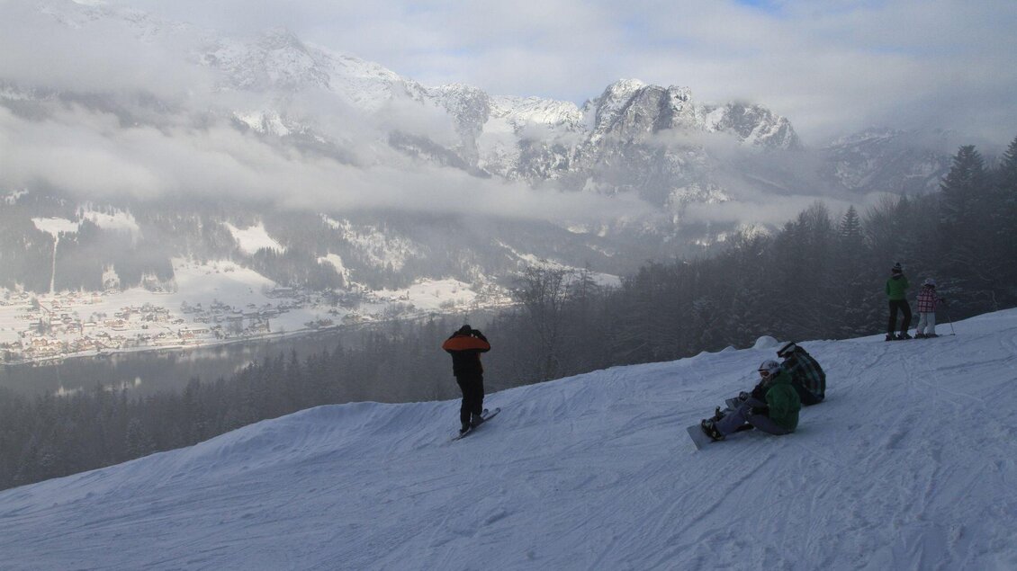 Ein verschneiter Berg mit Skifahrern im Vordergrund. Im Hintergrund sind die Berggipfel und Nebel zu sehen. | © Zlaim Lift/Franz Steinegger