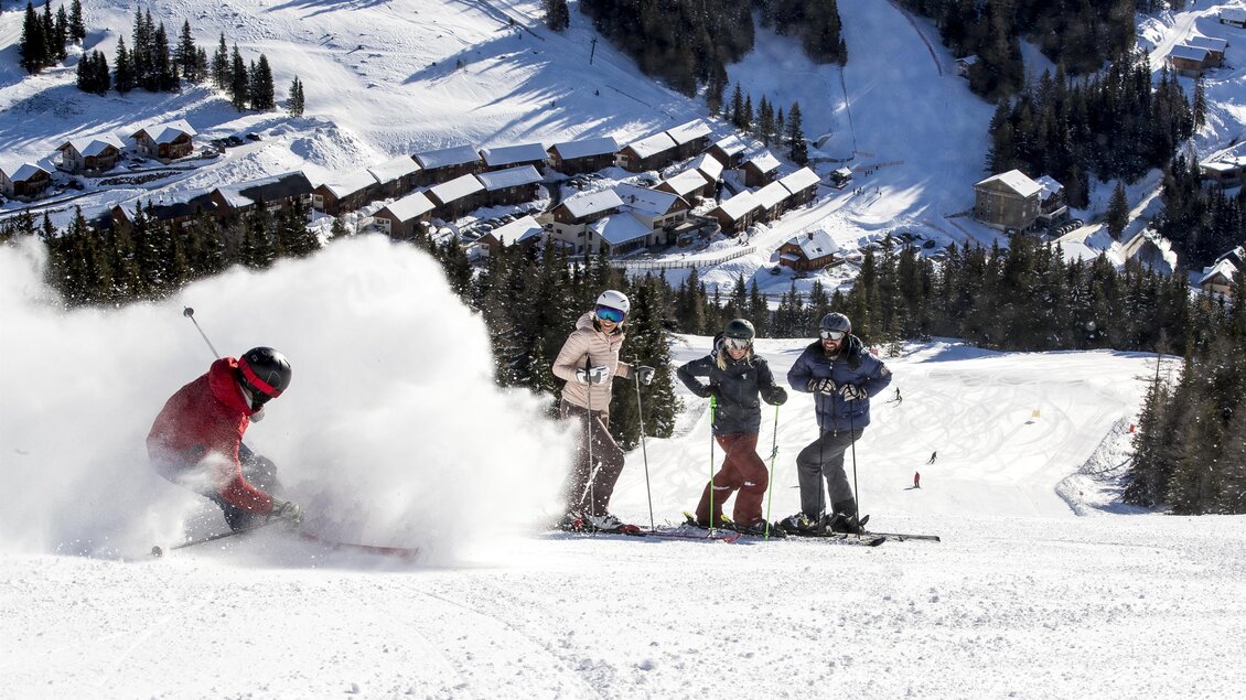 Eine lebhafte Skiszenen mit einem Skifahrer, der im Schnee schwankt. Im Hintergrund sind schneebedeckte Hügel und eine Gruppe von Skifahrern zu sehen. | © Lachtal-Lifte u. Seilbahnen GmbH