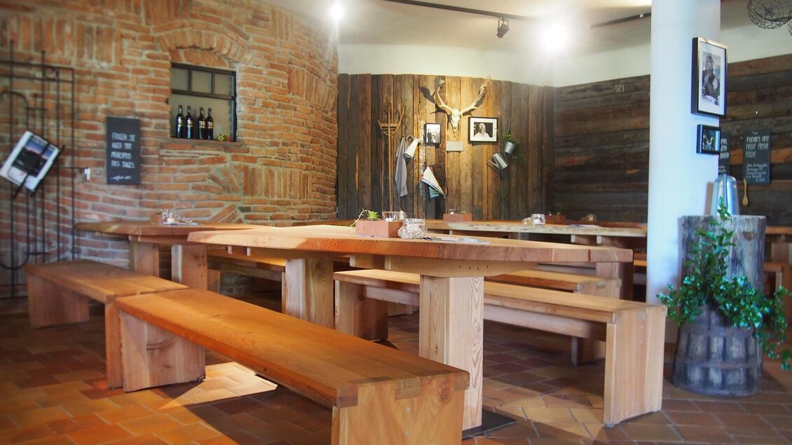Ein gemütliches Restaurant mit Holzstühlen und Tischen. Die Wände sind mit Backstein und Holz verkleidet, was eine einladende Atmosphäre schafft. | © Rogner Bad Blumau