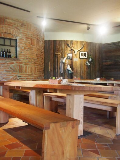 A cozy restaurant with wooden chairs and tables. The walls are clad in brick and wood, creating an inviting atmosphere. | © Rogner Bad Blumau