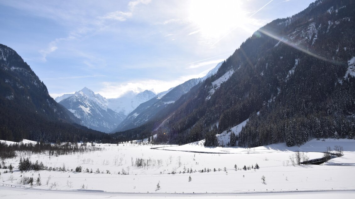 Eine winterliche Berglandschaft mit schneebedeckten Hügeln und hohen Bergen. Der Himmel ist klar mit strahlender Sonne. | © Sondl-Alm