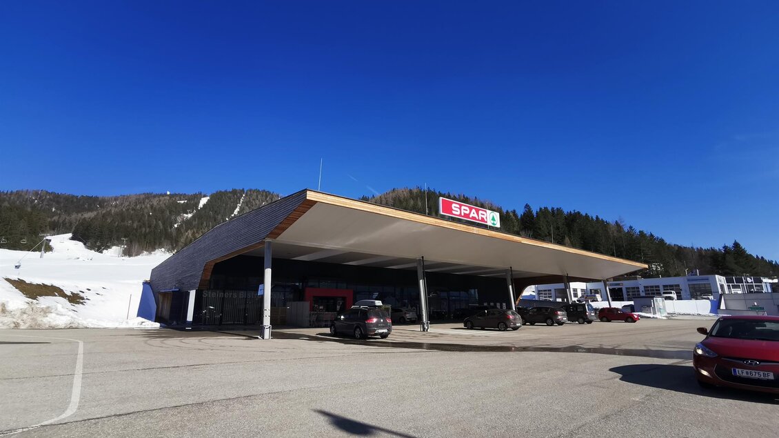 Ein modernes Geschäft mit überdachtem Eingang in den Bergen. Im Hintergrund sind schneebedeckte Flächen und Bäume zu sehen. | © TV Hochsteiermark | Brigitte Digruber