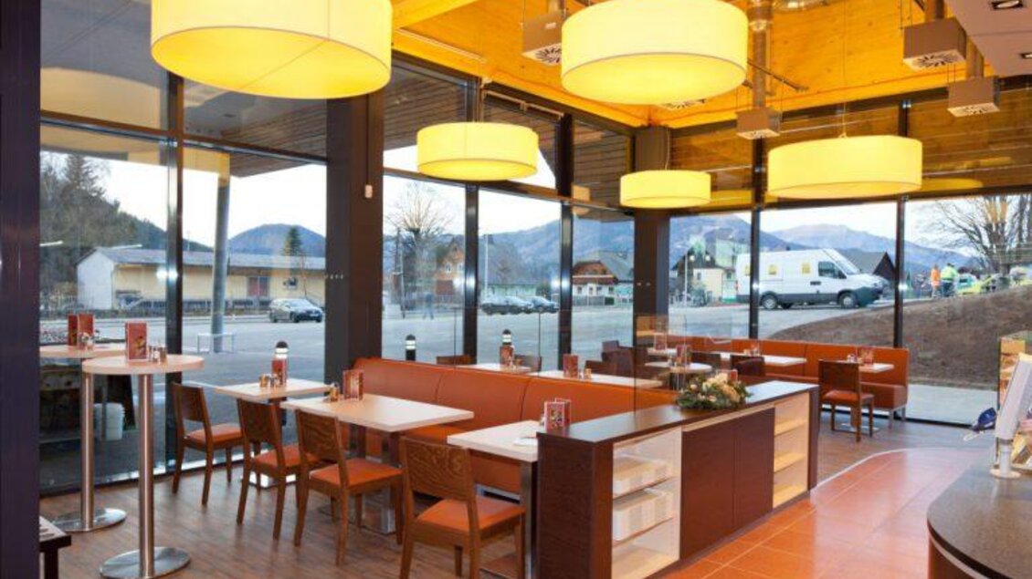 Ein modernes Restaurant mit viel natürlichem Licht und großen Fenstern. Die Einrichtung ist stilvoll mit Holz- und Lichtelementen. | © www.sparsteiner.at