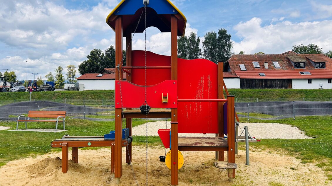 Ein Spielplatz mit einer bunten Rutsche und einer Kletterstruktur aus Holz. Der Bereich ist von Sand umgeben und es gibt einige Bäume im Hintergrund. | © Tourismus Vorau