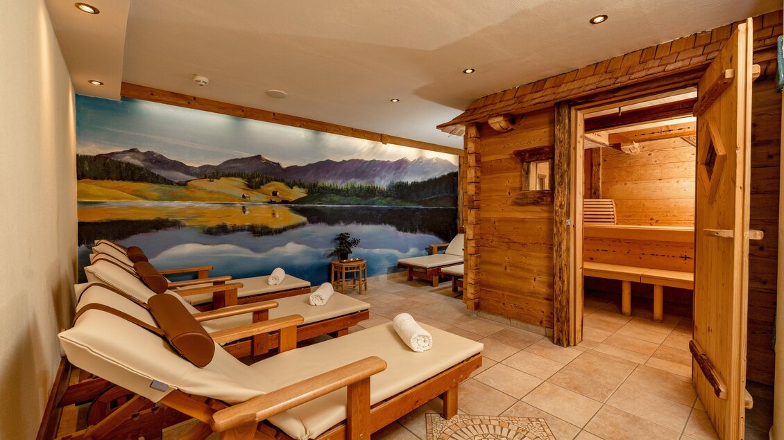 Ein entspannender Wellnessbereich mit Liegen und einer Sauna. An der Wand ist ein schönes Landschaftsbild zu sehen. | © baerenwirt.com