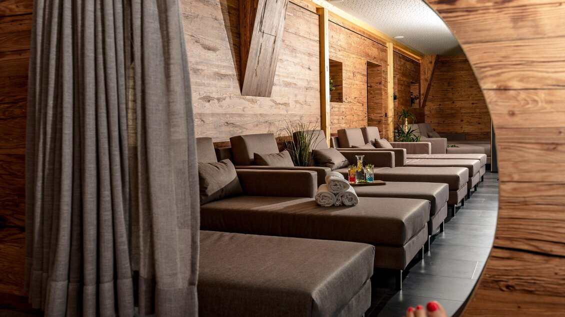 Ein entspannender Raum mit bequemen Liegen und warmen Holzverkleidungen. Durch einen runden Durchgang sind die Liegen gut sichtbar. | © Bärenwirt