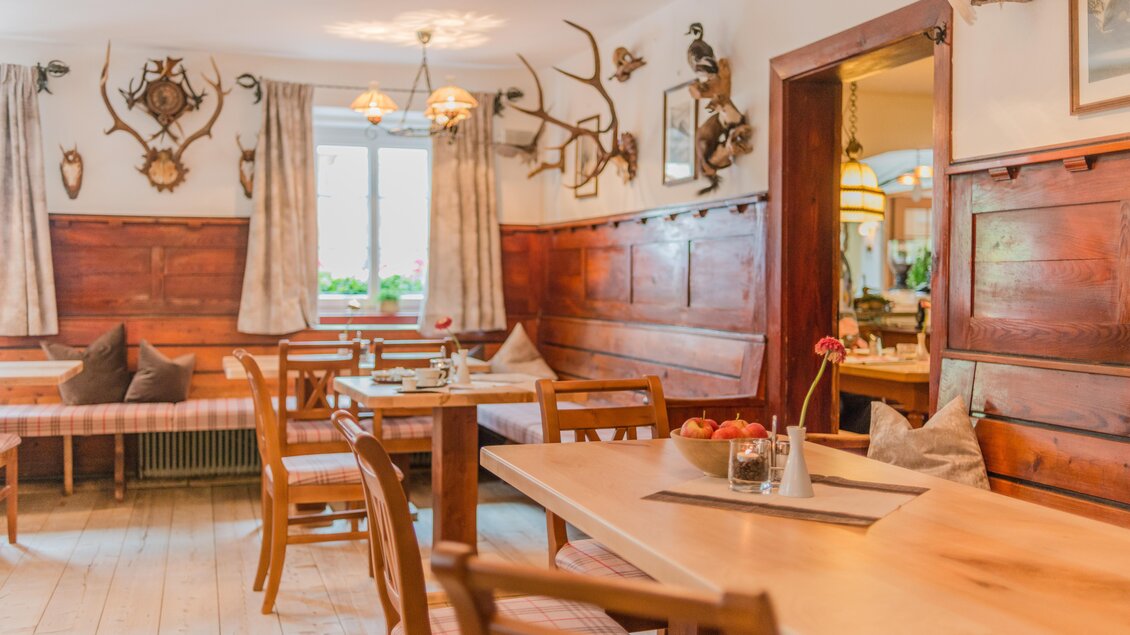 Ein gemütliches Restaurant mit Holztischen und Bänken. Wände sind mit Jagdtrophäen dekoriert und es gibt viel Tageslicht. | © Bärenwirt