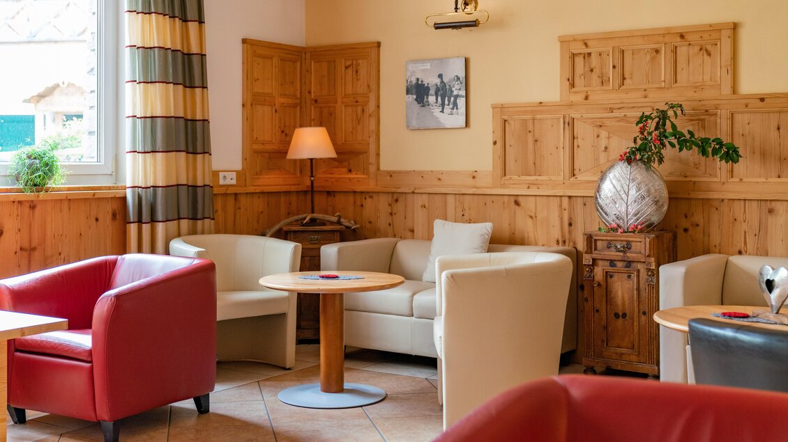Ein gemütlicher Aufenthaltsraum mit Holzwänden und bequemen Möbeln. Rote und helle Sessel sowie Tische laden zum Entspannen ein. | © baerenwirt.com