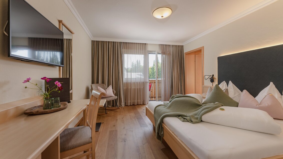 Ein modernes Hotelzimmer mit einem Doppelbett, einem Holztisch und angenehmer Beleuchtung. Große Fenster sorgen für viel Tageslicht und einen Blick nach draußen. | © Bärenwirt