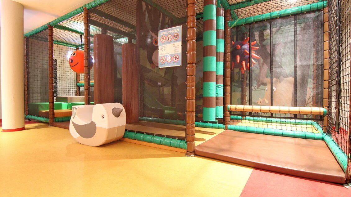 Ein Spielbereich mit bunten, gepolsterten Strukturen und einem großen Netz. Es gibt Rutschen und Kletterelemente für Kinder. | © baerenwirt.com