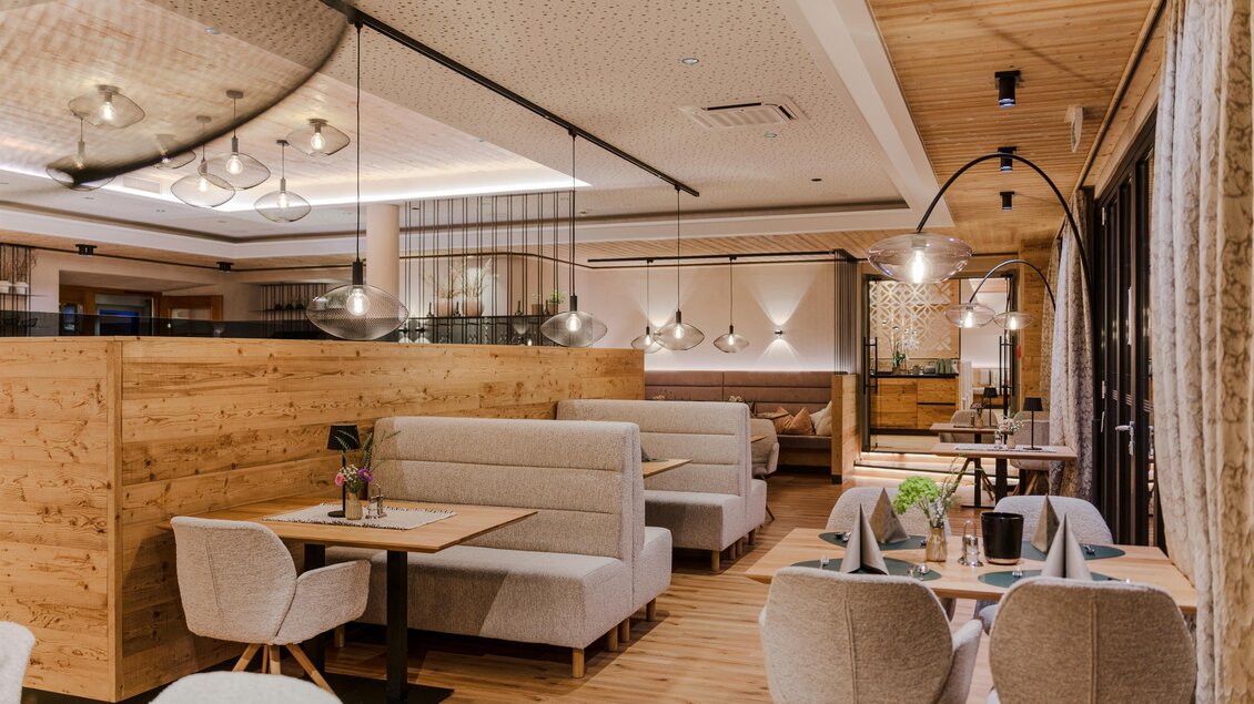 Modern eingerichtetes Restaurant mit gemütlichen Sitznischen, Holzwänden und stilvoller Beleuchtung. Auf den Tischen stehen Blumen und gefaltete Servietten, die Atmosphäre wirkt warm und einladend. | © Bärenwirt
