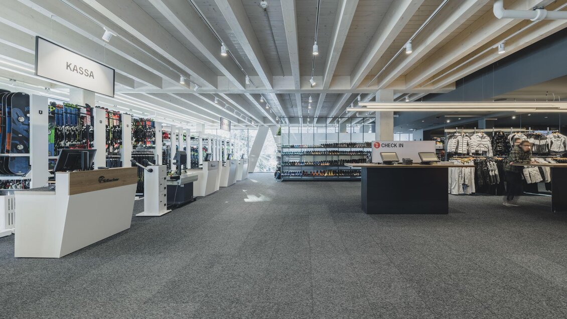 Ein geräumiges Sportgeschäft mit Regalen für Sportartikel und einer modernen Kasse. Große Fenster sorgen für viel Tageslicht und eine einladende Atmosphäre. | © Verleih