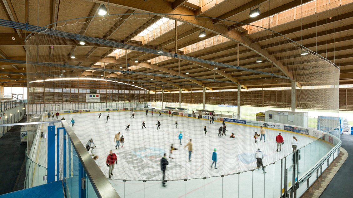 Eine Eishalle mit vielen Menschen, die fröhlich auf dem Eis Schlittschuh laufen. Der Innenraum ist hell und modern gestaltet. | © TV Region Graz - Rene Vidalli