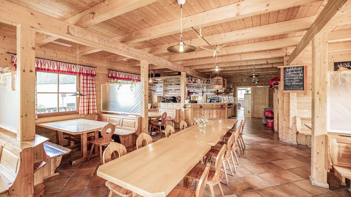 Ein gemütliches Restaurant mit Holzverkleidung und großen Tischen. Viel Tageslicht fällt durch die Fenster und sorgt für eine einladende Atmosphäre. | © Thomas Sattler