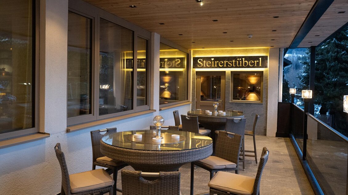 Ein gemütlicher Außenbereich mit runden Tischen und Stühlen. Die warm beleuchtete Atmosphäre lädt zum Verweilen ein. | © Herbert Raffalt