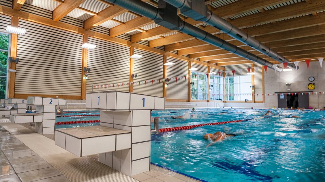 Das Sport Union Hallenbad mit mehreren Bahnen und Sprungblöcken. Die Umgebung ist hell und freundlich, mit großen Fenstern für Tageslicht. | © Michael Jöbstl