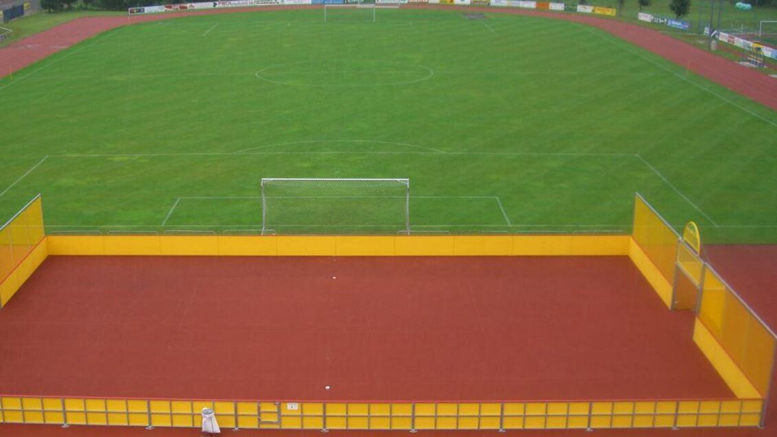 Ein Fußballplatz mit grünem Rasen und einem Tor. Vor dem Platz befindet sich ein Spielfeld mit gelben Wänden. | © Marktgemeinde Stainach-Pürgg