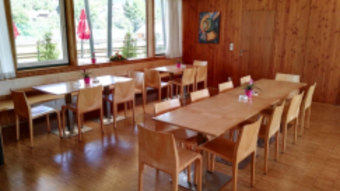 Ein gemütlicher Innenraum mit Holzwänden und großen Fenstern. Tische und Stühle warten auf Gäste und sind stilvoll dekoriert. | © Stadionstüberl Bad Aussee (c) Jochen Kreidl