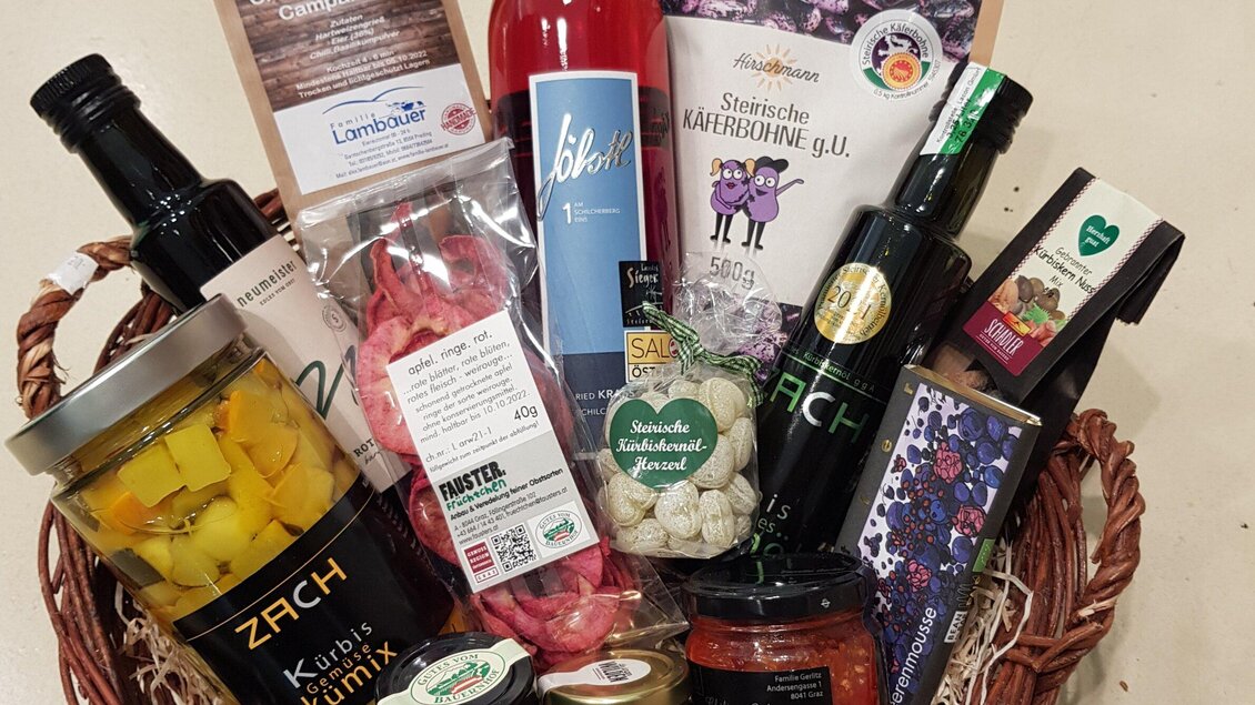 Ein Geschenkkorb mit einer Auswahl an regionalen Lebensmitteln und Getränken. Enthält Flaschen, Snacks und Delikatessen in sorgfältig angeordnetem Layout. | © Mach Genussprodukte GmbH - Julia Trenker