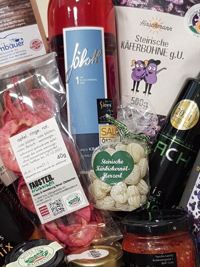 Ein Geschenkkorb mit einer Auswahl an regionalen Lebensmitteln und Getränken. Enthält Flaschen, Snacks und Delikatessen in sorgfältig angeordnetem Layout. | © Mach Genussprodukte GmbH - Julia Trenker