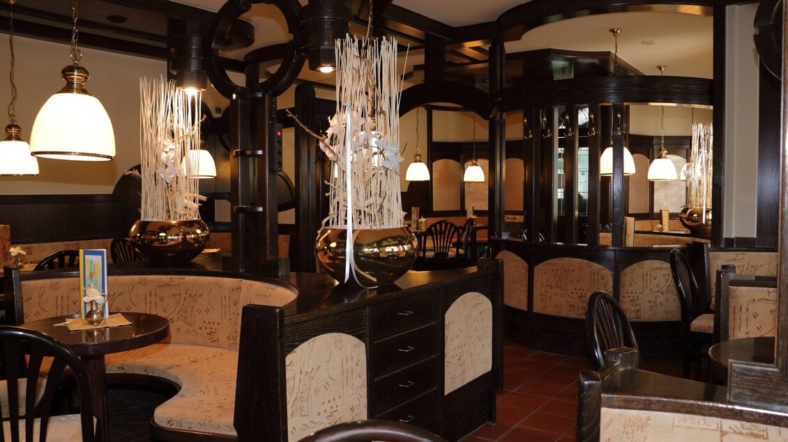 Ein gemütliches Café mit dunklem Holzdekor und eleganten Beleuchtungskörpern. Die Sitzgelegenheiten sind komfortabel und einladend gestaltet. | © Stadtcafe Pötscher