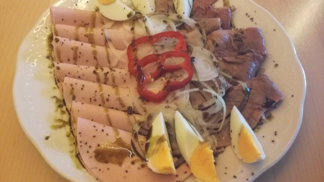 Ein Teller mit verschiedenen Wurst- und Fleischsorten, dekoriert mit Eiern und Paprika. Das Gericht ist ansprechend auf einem weißen Porzellanteller angerichtet. | © Stadtheuriger Trofaiach