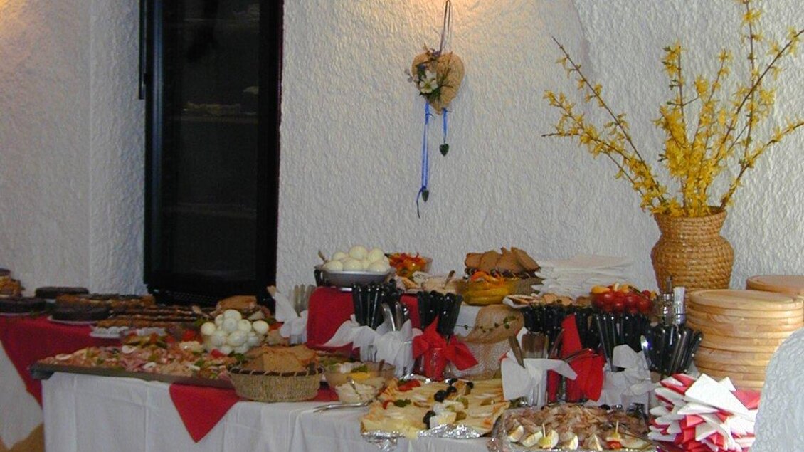 Ein festlich gedeckter Tisch mit verschiedenen Leckereien und Snacks. Die Dekoration in Rot und Gold sorgt für eine einladende Atmosphäre. | © Stadtheuriger Trofaiach