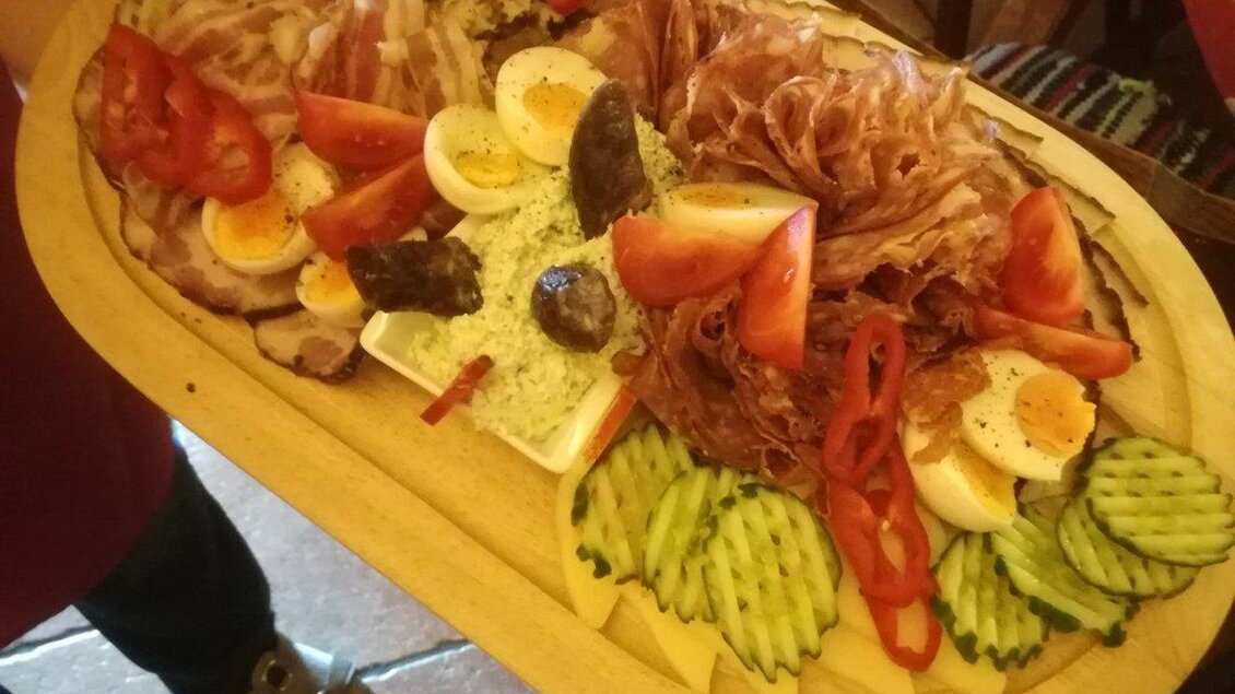 Ein schön angerichteter Teller mit verschiedenen Wurst- und Käseaufschnitten, Eiern, Tomaten und Gurken. Der Teller ist auf einem Holzbrett serviert und sieht sehr appetitlich aus. | © Stadtheuriger Trofaiach