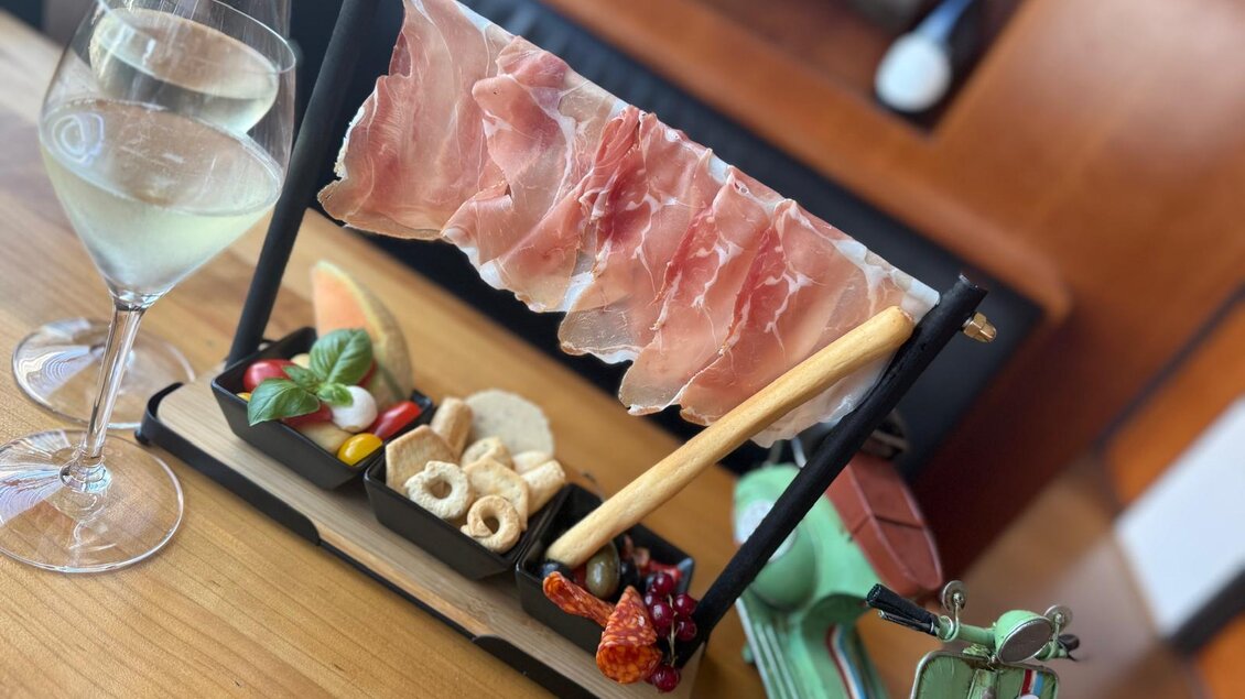 Eine stilvolle Präsentation von Aufschnitt mit frischem Gemüse und Beilagen. Dazu ein Glas Wasser auf einem Holztisch. | © TV Südsteiermark - Elvira Kos-Czerniecki