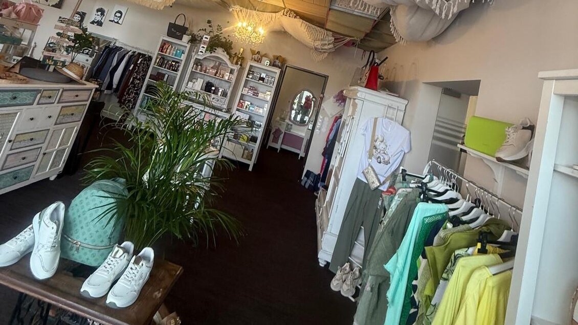 Ein einladendes Geschäft mit Kleidung und Schuhen. Es gibt Regale mit verschiedenen Modeartikeln und eine Pflanze in der Mitte des Raumes. | © TV Südsteiermark - Elvira Kos-Czerniecki