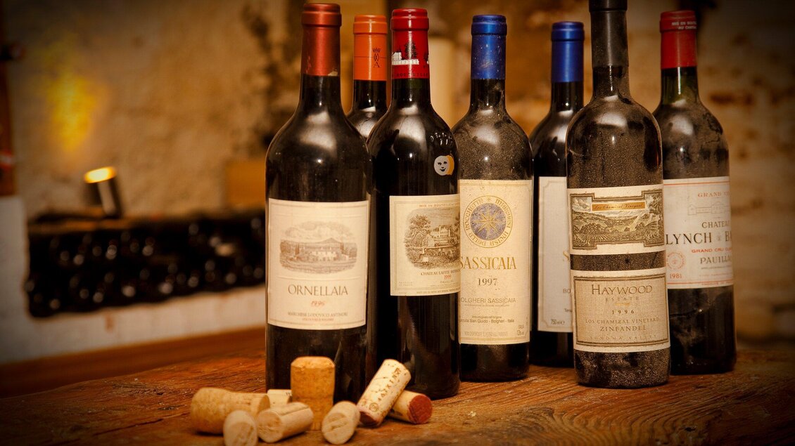 Eine Auswahl verschiedener Weinflaschen auf einem Holztisch. Einige Korken liegen daneben. | © Stainzerbauer
