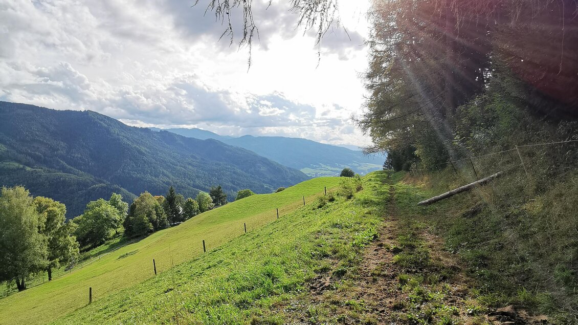 Eine malerische Landschaft mit sanften Hügeln und üppigem Grün. Die Sonne strahlt durch die Wolken und sorgt für eine angenehme Atmosphäre. | © Landentwicklung Steiermark