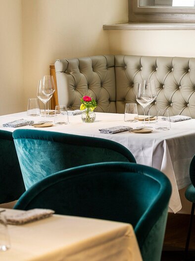 Ein elegantes Restaurant mit einem schön gedeckten Tisch und stilvollen Stühlen in Türkis. Die Atmosphäre ist gemütlich und einladend. | © Stammtisch - Paul Stajan