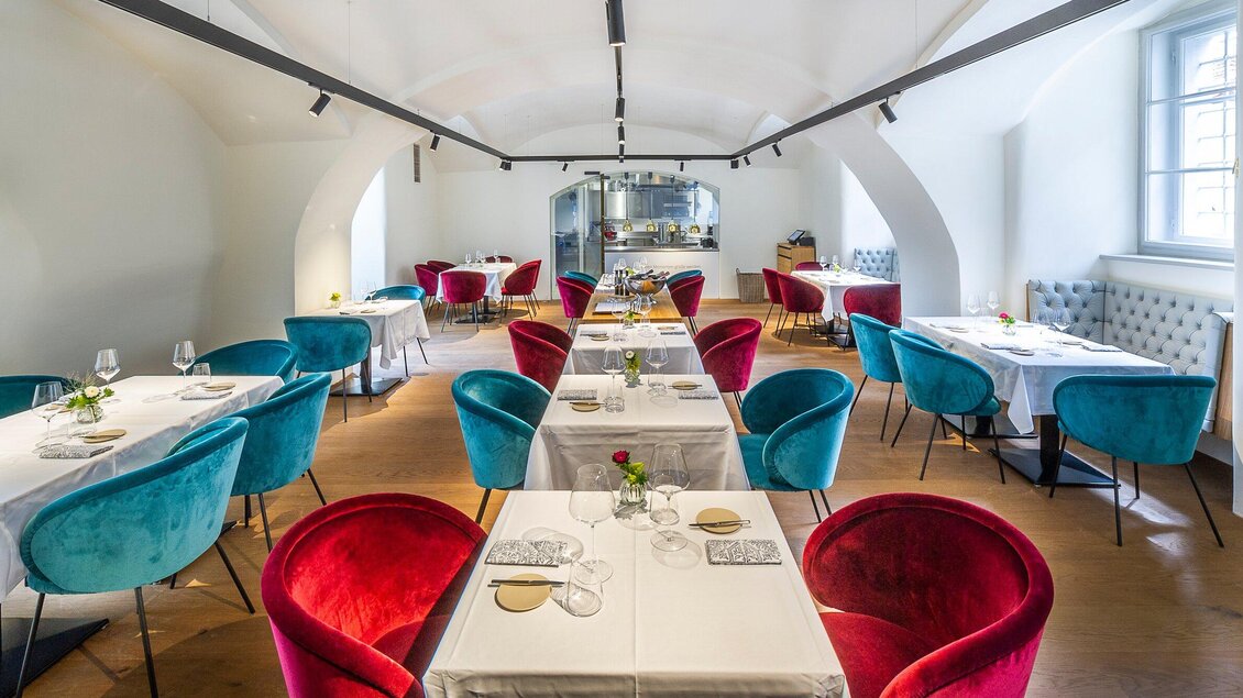 Ein elegantes Restaurant mit stilvollen Tischen und bunten Stühlen. Die Atmosphäre ist hell und einladend. | © Stammtisch - Paul Stajan